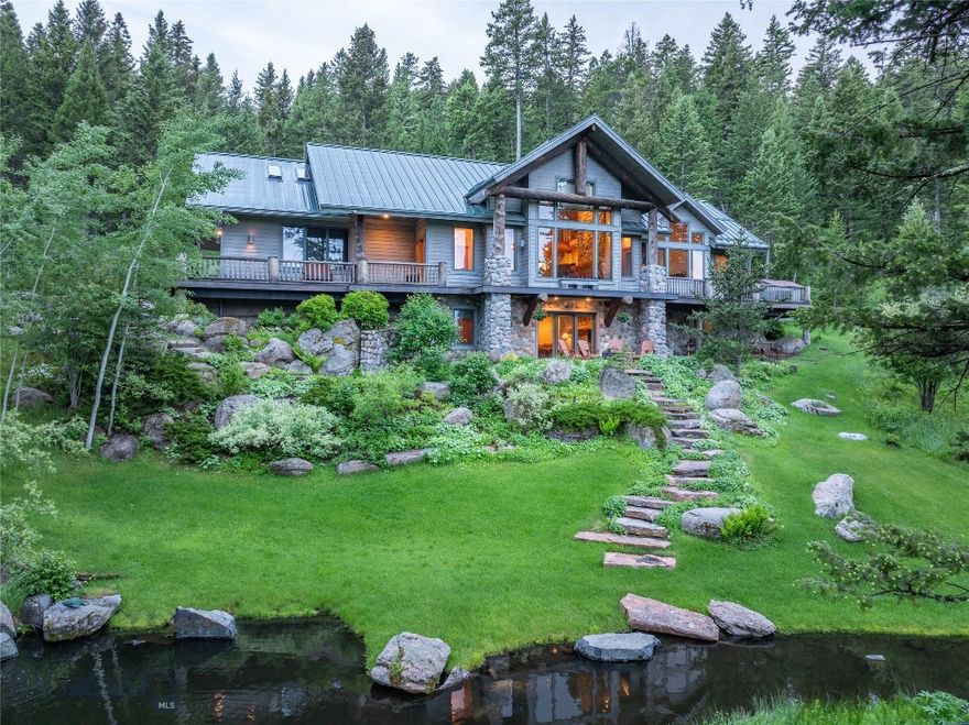 Welcome to 709 Limestone Road, a serene mountain retreat tucked into the forested hills of the exclusive Eagle Rock Reserve in Bozeman, Montana. Designed by renowned architect Faure Halvorsen and built by Jim Syth, this custom 4,516 SF home sits on 20 lush acres, offering a rare combination of privacy, tranquility, and proximity to town—just 15 minutes from downtown Bozeman. Set among mature trees, wildflowers, and professionally landscaped gardens, the property features two peaceful ponds with cascading water features, creating a park-like setting that invites relaxation and exploration. From the main living area, expansive windows frame stunning views of the Bridger Mountains, while the rest of the home is nestled in a canopy of evergreens, creating a true retreat atmosphere. Inside, thoughtful design and craftsmanship are evident throughout. The main level includes a spacious great room with vaulted ceilings, a floor-to-ceiling wood-burning stone fireplace, and rich wood accents that echo the natural surroundings. The open-concept layout flows seamlessly into the dining area and kitchen, making it ideal for gatherings. The main floor also features a private primary suite with serene garden views, offering easy single-level living. Downstairs, the walkout lower level includes a large family room with a second fireplace, three additional bedrooms, two full bathrooms, and direct access to a covered patio—perfect for guests or multigenerational living. The upper level offers a bright loft space and two office/studio rooms, ideal for creative work or remote professionals. Multiple outdoor living areas—including a wraparound deck, covered patio, and quiet sitting areas tucked into the trees—make the most of Montana’s long summer days and star-filled nights.
As part of Eagle Rock Reserve, residents enjoy access to a private equestrian facility, a stocked trout pond, community-maintained trails, and adjacent State Land for hiking, horseback riding, and outdoor adventures. With nearby access to Triple Tree Trail and National Forest lands, this home is a gateway to the Montana lifestyle—peaceful, private, and connected to nature, yet minutes from all that Bozeman has to offer.