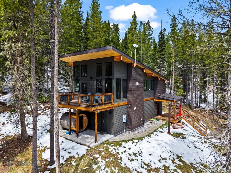 Your mountain-modern ski chalet awaits! Nestled among the pines near the base of the famed Bridger Bowl, this 3-bedroom retreat is the ultimate basecamp for adventure. Each bedroom features its own private bath, creating an ideal layout for hosting groups, families, or vacation guests.

The open-concept great room is designed for gathering, with soaring ceilings, exposed timbers, and an airy, inviting feel. Expansive windows showcase wooded views while maintaining a sense of privacy.  Radiant in-floor heat and a gas fireplace keep the space warm and cozy during the ski season. Sip your morning coffee on the elevated deck as wildlife wanders through the trees, or unwind after a day outdoors on the custom chairlift swing or within the electric 6-person cedar barrel sauna.

After a day on the slopes, enjoy the convenience of the back door, where dedicated ski storage with boot and glove dryers plus ski racks makes storing your gear effortless.

Located in the B-4, Bridger Bowl Base Area Zoning District, which allows for overnight accommodations, this property has operated since its inception in 2020 as a successful short-term rental (STR), offering flexibility for personal use along with excellent income generation. The summer season has proven to be just as busy, or even busier than winter, for STR income with year round recreation just outside your door. Cross-country ski trails, hiking and biking trails, National Forest access, and Bridger’s famous cold smoke are all just steps away from the front door. Offered fully furnished, this property is truly turnkey and ready to enjoy. Call Today for your private tour.