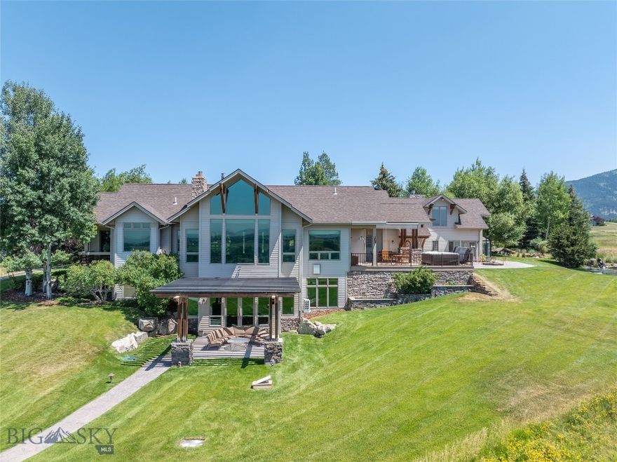 Located on arguably one of the best lots in Triple Tree Ranch with panoramic views of the Spanish Peaks and Tobacco Root Mountains, 585 Wildrose Lane is an exceptional property thoughtfully designed for both grand entertaining and quiet retreat. This 7,288 SF residence, designed by Locati Architects and built by Joe Mahar, features 4 bedrooms, a pass-through bunk room, and 4 ½ baths. Upon entering the home, prepare to be astounded by the picture windows framing the incredible valley and mountain views. The two-story stone fireplace anchors the main living area, connecting to the open-concept kitchen and dining area with a coffee bar and access to outdoor entertaining space with hot tub and firepit. On the main level you’ll also find a spacious mudroom, laundry with powder bath, and a generous primary suite with walk-in closet, jet tub, tiled shower, and private balcony. A heated 3-car garage includes a large hobby space that connects to a solarium with dog wash and garden access. Upstairs features a playroom, pass-through bunk room, bedroom, three-quarter bath, and a stunning library/office with wood-burning fireplace and built-in bookshelves.  The lower level walkout includes two bedrooms, a full bath, a large family room with gas fireplace and built-ins, a card room with poker table, wet bar, and a subterranean wine cellar accessible via elevator or garage. Additional highlights include in-floor radiant heat, gas-forced air with AC plus additional systems, creating year-round comfort. Extensive mature landscaping surrounds the home with stamped concrete paths, and a pond feature with lily pads, waterfall, and moose sculpture. Backing to community open space, this home offers unmatched privacy, stunning natural beauty, and unique features rarely found in the Bozeman market.