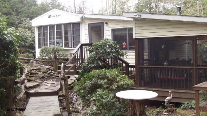 Enter your own private Shangri-La, a permanently happy land, isolated from the outside world according to Wikipedia.  Your privacy is guarded by the fencing at the road while inside you are relaxing on the screened in deck as you listen to the gurgling stream that runs underneath the deck and throughout your property.  The foliage and yard dcor blends together without being overbearing.  Inside you can stretch out and have room for the whole family.  The park model has a bedroom, eat in kitchen, full bath, and your washing machine.  An addition provides a great room with a wood/coal stove to take the edge off cool fall nights and a half bath in they storage/dryer room.  Add to that the screened in deck and a storage shed.  Need to go to the pool-take the included golf cart.