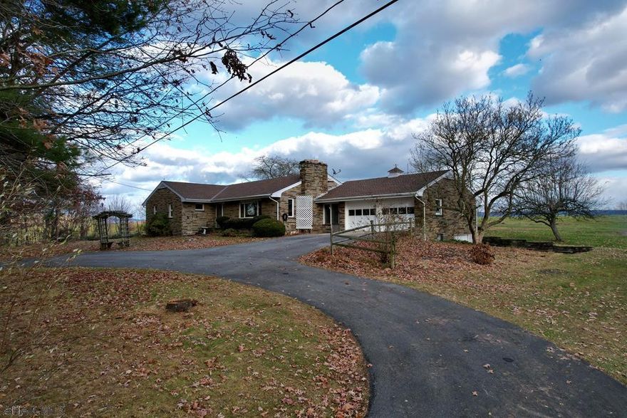 Stone Ranch home with 3 BR, 3 baths on 7.29 acres with beautiful views. 5 acres wooded and 3 car garage, workshop.  This home has beautiful hardwood flooring under carpets.  This home is very spacious and close to town but very private.  Could be a great weekend property for very large family, lots of closets and rooms are spacious.
