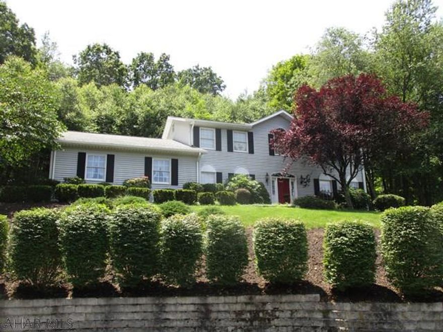 Two-story center hall colonial home resting just outside the Bedford Borough. The main level features a front foyer, living room w/ hardwood floors, dining room w/ hardwood floors, kitchen w/ island & built-in desk, family room with wood fireplace, den/office, laundry room and a half bath. Second level has a full bath, four bedrooms; one is a master suite with full bath and walk-in closet. Heat pump w/ central air, two-car attached garage, rear screened in porch and macadam driveway. Full basement that is partially finished and also contains a work shop area. Large lot with .385 of an acre and private rear yard.