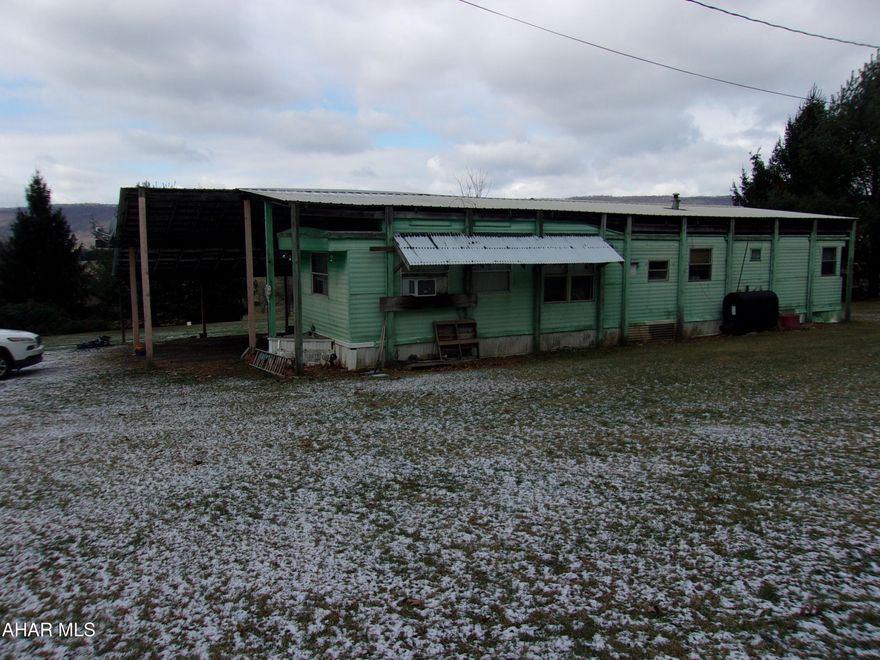With some TLC, this 1969 singlewide with addition could be a weekend getaway, maybe a hunting camp, or even a full time residence. Large carport roof extends to cover the trailer and addition.