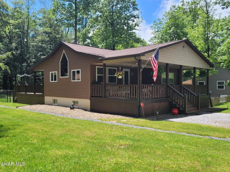 First impressions mean a lot.  Walk up on this expansive front porch and you will be impressed.  If that isn't enough, the large open deck in the rear offers more private outside space for your family to relax and enjoy a view of the woods.
Inside, the kitchen / living room continues the spacious feeling with a cathedral ceiling and multiple windows that light up your life.   
There are two bedrooms and a full bath to complete this one level home.
Travel to the basement for a large finished family room or guest room.  Another full bathroom adds convenience for all.  A laundry and utility room are located here.  The basement can also be accessed from the walk out entrance.  
A portion of the back yard off the deck is fenced in for the safety of children or pets.
Two sheds, one with a garage door,  offer storage for your tools and toys. 

Make this your weekend getaway or full time  comfort zone.

Seller may need time to find suitable housing.