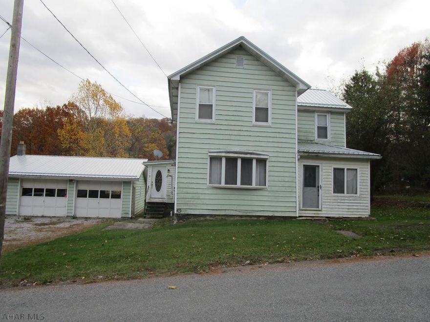Vinyl sided two story home with metal roof, featuring 3 bedrooms, 1st floor laundry room and bath, oak front kitchen cabinets and living room with pellet stove. Enclosed porch and a detached two car garage with woodburner.  Large lot.
