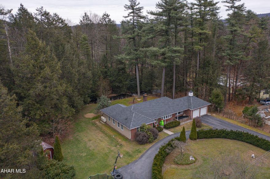 One level living in this large ranch style home.  Perfectly situated on 1.33 acres of natural beauty.  Mature trees shade this large slightly sloping yard.  A lovely stream divides the yard from a wooded nearly 1/3 remaining acres. Pull into your two-car heated garage via a paved u-shaped driveway.  Inside you will find thoughtfully and tastefully updated home features including newer windows, a large, remodeled bathroom and gorgeous hard wood floors.  First floor laundry-mud room with a door to the back yard.  A walk-up attic provides plenty of storage space. Just minutes from I-99, this property is conveniently accessible to State College and Altoona areas