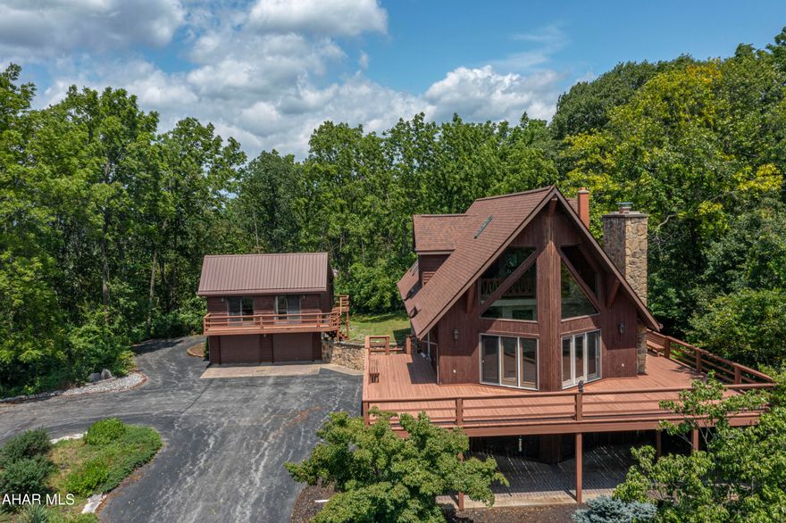 Welcoming and charming —this beautifully maintained, one-owner home sits on over 3 acres of peaceful land, offering unmatched privacy and stunning panoramic views. With a classic wrap-around deck and thoughtfully designed spaces both inside and out, this property is unique and a great opportunity to own a space with both comfort and versatility. 

Inside the main home, you'll find 3 spacious bedrooms and 3 full bathrooms, including a first-floor bedroom and bath. The living areas are surrounded by large windows that frame the scenic landscape, filling the home with natural light.

The finished basement offers cozy, extra living space centered around a gorgeous stone fireplace and includes its own full bathroom—perfect for entertaining or unwinding.

Additional features include:

Newer central air system for year-round comfort

Attached 1-car garage plus a circle driveway for easy access

Detached 3-car garage with a spacious apartment above—complete with a full kitchen, dining room, large living room, full bathroom, and 1 bedroom. A perfect setup for guests, rental income, or a private home office.