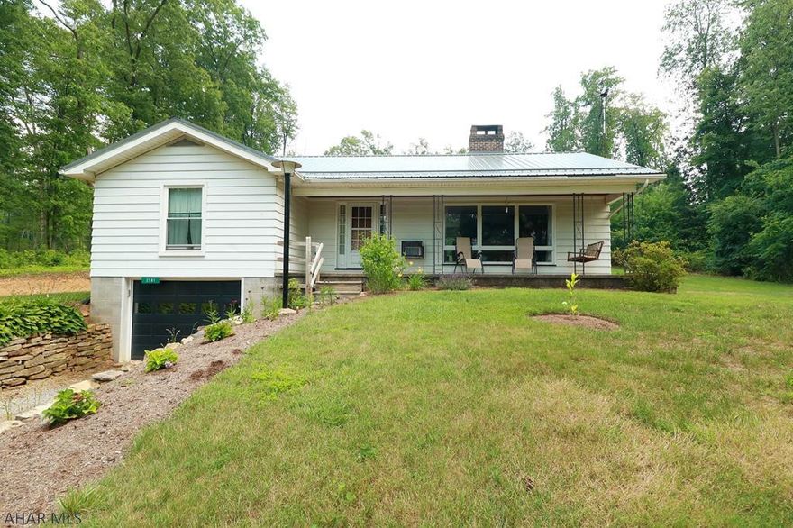 Resting peacefully atop a gently sloping full acre lot, this cozy ranch delivers a covered front porch that leads you to the charming interior.  Hardwood floors, brick fireplace & wall of windows greets you in the living room.  The dining room delivers a new sliding glass door to the new deck, hardscape & concrete paver patio overlooking the tranquil back yard.  The kitchen boasts included stainless appliances.  There are 3 bedrooms & a full bath with added shower enclosure & new window.  The unfinished basement delivers plenty of storage space, is radon mitigated & a 1 car integral garage.  Additional highlights include a new metal roof, pavilion/pole shed, French drain & added an on demand propane water heater.  Located off the beaten path in the Tyrone School District.