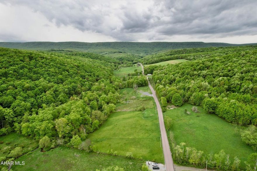 Own a piece of heaven with this tranquil land.  Situated in the foothills of the Allegheny Mountain is this beautiful piece of land.  Sit and listen to the rolling stream as it runs through the trees and across the stones. Dream of the perfect location to build a dream home, vacation home, or hunting cabin. The property is made of woods, sloped rolling hills, pasture, and crop fields.  The property has 2 wells, 2 sewer systems, 2 ponds one for each side of the road. The property is divided by the road giving the ability for those who want two locations for a house, maybe an investment opportunity, or barn/work shop with water and sewer.  So many possibilities! Close to Shawnee State Park, Blue Knob State Park, Gallitzin State Park, and so much more.