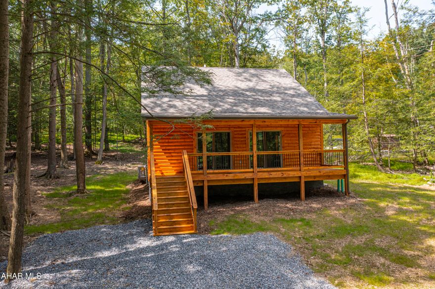 If you have ever dreamed of living in a log cabin in the woods, but are not interested in ''roughing it'', take a look at this beautiful home.  Sit on the full front porch and watch the deer and other wildlife.  Step inside to the open great room with a cathedral ceiling.  The kitchen boasts hickory cabinets and stainless steel appliances.  The first floor bedroom, bath and laundry offers one floor living if that is what you are looking for.  But you will want to slip up the lovely staircase to see two large additional bedrooms sharing a Jack and Jill full bathroom.  
A full basement offers loads of storage or the potential for additional living space.
Heat and central air are provided by heat pump with auxiliary propane heat.
This home is on a private road, but located not far from the club house and swimming pool.
