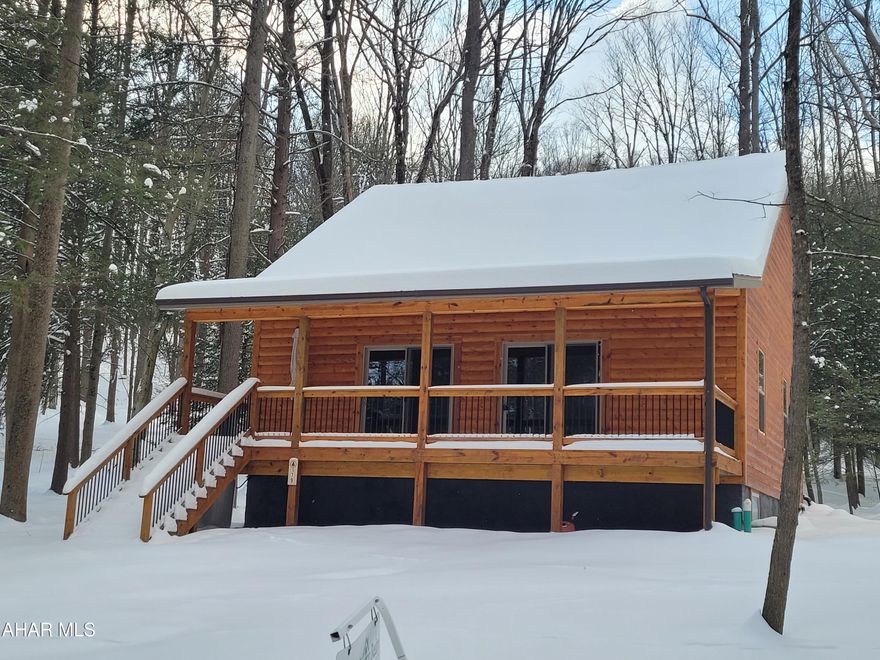 Motivated Seller!  If you have ever dreamed of living in a log cabin in the woods, but are not interested in ''roughing it'', take a look at this beautiful home.  Sit on the full front porch and watch the deer and other wildlife.  Step inside to the open great room with a cathedral ceiling.  The kitchen boasts hickory cabinets and stainless steel appliances.  The first floor bedroom, bath and laundry offers one floor living if that is what you are looking for.  But you will want to slip up the lovely staircase to see two large additional bedrooms sharing a Jack and Jill full bathroom.  
A full basement offers loads of storage or the potential for additional living space.
Heat and central air are provided by heat pump with auxiliary propane heat.
This home is on a private road, but located not far from the club house and swimming pool.