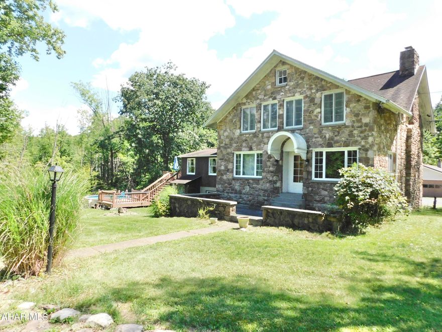 Welcome to the sweetest home that is nestled on over 5 acres in Sinking Valley.  You will instantly fall in love with its one of a kind stone exterior. Inside you will be greeted with stunning hardwood floors and a beautiful wood burning fireplace.  The kitchen has been so tastefully updated with b granite countertops and stainless steel appliances.  
In this home, entertaining is made easy!  Off the kitchen you can enjoy a fantastic game room complete with a corner bar area!  This room has not 1 but 2 different floor to ceiling sliding glass doors that lead to the wrap around deck.  Friends and family can cool off in the above ground pool or sit and enjoy the wooded views of your incredible backyard.
The detached garage is a wonder of its own!  Four separate bays allow for plenty of storage and workspace.  Through the end bay you will find an oversized office space with a private entrance.  With a little elbow grease, the potential of this space is endless.
The included guest house that sits above the property has recently undergone a much needed facelift with a brand new roof and fresh exterior paint.  This house is complete with 3 bedrooms and 1.5 bathrooms.  The master bedroom is conveniently located on the main floor where you will also find the full bath and laundry.  Currently, this home is rented for 850 a month and is a great way to offset your own monthly payments!
Call today for any questions or to schedule your private tour.