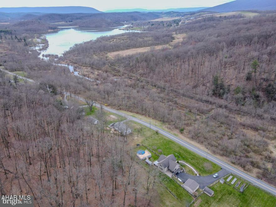 Nestled on 1.26 acres of tranquil land, this Canoe Creek Retreat beckons with its charming chalet-style architecture and abundant outdoor space. Boasting 4 bedrooms and 2 full baths, this inviting home promises a haven of relaxation both inside and out. Step into the bright interior, where a newly renovated kitchen awaits, adorned with gleaming granite countertops, ample cabinet space, and a central island perfect for culinary endeavors and entertaining alike. The adjacent dining area seamlessly connects to the rear deck, offering an ideal setting for al fresco dining amidst the serene surroundings. Cozy up in the living room, complete with a wood-burning stove and elegant wood floors, or retreat to the sun-soaked Florida room, where a 6-person hot tub awaits amidst sliding privacy windows, providing year-round comfort and relaxation. The main level also hosts the primary bedroom, boasting a spacious closet area and a luxurious full bath featuring a walk-in tiled shower, heated toilet seat, and dual sinks for added convenience and comfort. Ascend to the newly carpeted upper level, where two generously sized bedrooms await, one of which boasts a bird's eye view balcony overlooking the lake. A second full bath and ample storage space complete this level. For additional living space, the basement offers versatility, accommodating a study, play area, gym, or a potential fourth bedroom or home office. A large dry utility area provides ample storage, ensuring organizational ease. Outside, the property features three fenced areas, ideal for pets or children, along with raised garden beds and an above-ground pool surrounded by expansive decking, perfect for outdoor recreation and relaxation. A 2-car detached garage and spacious driveway provide ample parking, while mature perennials and trees enhance the scenic landscape. Conveniently located within walking or biking distance to the serene Canoe Creek State Park, residents can enjoy a myriad of recreational activities, including boating, camping, hiking, and swimming, making this property an idyllic retreat for nature enthusiasts and families alike. Don't miss the opportunity to make Canoe Creek Retreat your new place to call home.