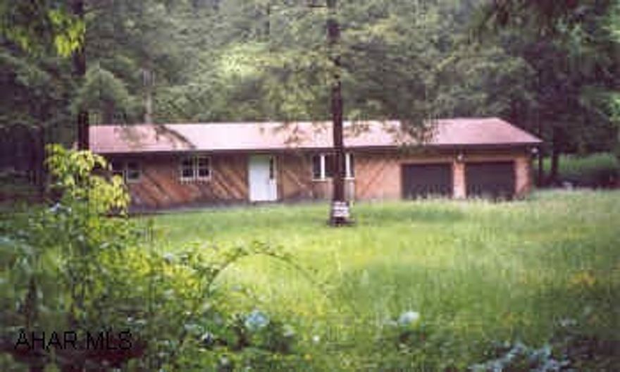 House is under roof, completely framed out, well & septic, electric to property.  1 acre with trout stream, front yard, very private, cedar siding.  1 story, 2 car attached garage.