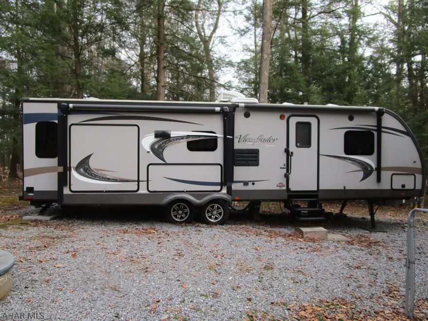 Gorgeous upscale camper with two slide outs.  Kitchen has an island.  Located on a flat lot with private woods behind it.  There is an outside kitchen built in to the camper.
