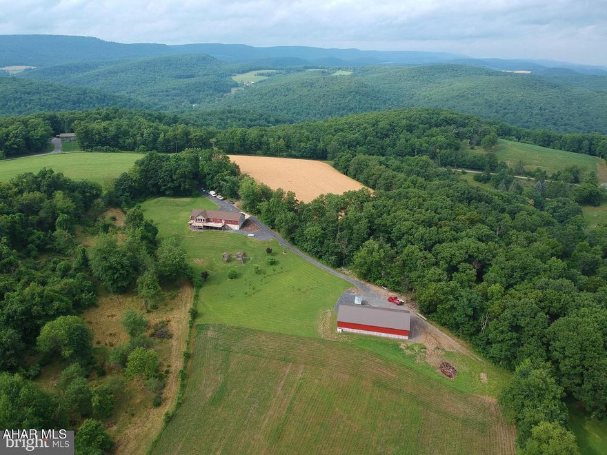 Welcome to your private retreat nestled on 23 gently rolling acres where horses are welcome, views are endless, and opportunities abound. This expansive 4-bedroom, 3-bath home offers over 3,300 finished square feet of flexible living space—ideal for those who need room to spread out, entertain, or generate rental income. The main level is open and airy, starting with a mudroom/laundry area that connects to the thoughtfully designed galley kitchen with abundant cabinet and counter space. The kitchen flows effortlessly into the dining area and oversized living room, highlighted by cathedral ceilings, a gas fireplace, and a full wall of windows that showcase breathtaking mountain views. Enjoy direct access to a full-length deck from the living and dining spaces—perfect for relaxing or entertaining under the open sky and the view goes on forever. The spacious owner's suite features a private bath with a soaking tub and tiled walk-in shower. Two additional bedrooms and a second full bath complete this level, along with a 28x30 attached garage. The lower level is a fully finished walk-out offering exceptional flexibility. With its own entrance, a rec room with bar, kitchenette, full bath with tiled walk-in shower, bedroom, playroom/office, and generous storage space, this area is ideal as an AirBnB, in-law suite, or college student haven. Features a private concrete patio of it's own overlooking the amazing mountain and valley views. Outdoors, serenity surrounds you—from the open fields to the 40x80 heated garage/shop, complete with a batting cage for baseball or softball enthusiasts. Whether you're looking to house animals, grow your dream garden, or simply soak up the peace and quiet, this property delivers. Schedule your showing today and discover the freedom of countryside living with all the space you could ever need.