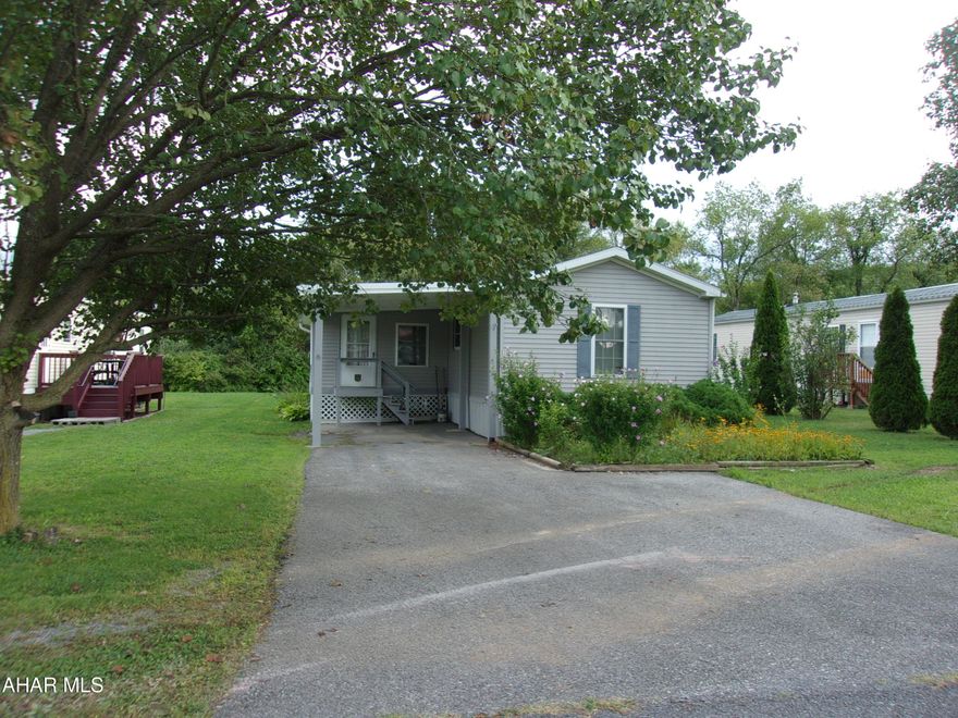 Come live at the Country Club!!!  Nice mobile home park in country setting, close to all amenities.  This 2004 singlewide has been well maintained and has many upgrades.  The carport protects from the elements and leads onto a covered porch.  Next is a three season room, which has lots of light.  The house has an open concept with living room, dining room, and kitchen.  Arrange your space however you want.  Countertop and cupboards galore in the kitchen - So Much Storage!  Primary bedroom has a walk-in closet and large ensuite with more storage space.  The covered back porch is perfect for enjoying morning coffee or relaxing after work.  
The lot is level with beautiful landscaping, mature trees, and wooded foliage in back for privacy. Enough room to have a garden and a shed to store your mower,  gardening equipment, and tools.