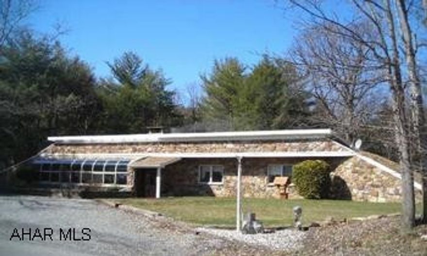 This earth-sheltered home is quite efficient in heating/cooling bills!  One owner home situated on 10+ acres in the beautiful area of White Sulphur Springs!  Acreage is mostly wooded, also has a stream!  Built solidly with block (reinforced with rbar and concrete), finished with a field stone exterior.  Field stone was all collected within a 10mi radius of the home!  Enclosed glass sunroom, french doors, additional baking area off kitchen, some ceramic floors, plaster walls, skylights, Anderson windows, water system, and  ample closet/storage space. Finished family area and the 4th bedroom with w-in closet and full bath, workshop in the basement.  Two garage accesses from home.  Shed stays, generator ready to be hooked-up.  Complete serenity here and a MUST see home!