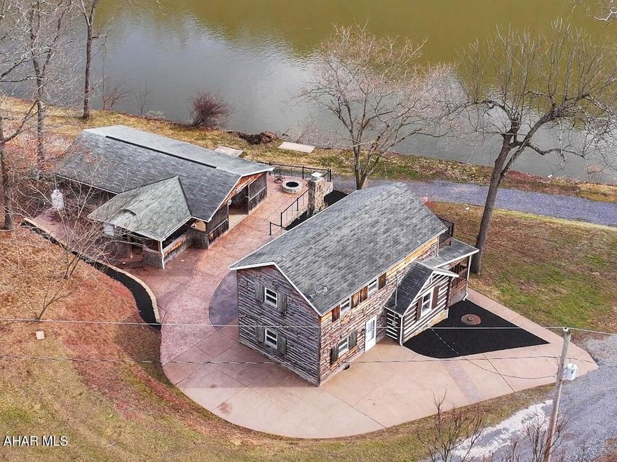 Own this fabulous getaway featuring a one-of-a-kind 1895 log cabin with hemlock sided addition perched above the Juniata River in Millin Beech. Inside, on the 1st floor you'll find modern amenities with the kitchen's six-burner gas stove, dishwasher, loads of cabinet space & overhead lighting, laundry area, 3/4 bath. Step back in time as you enter the living room, dining area with a stone woodburning fireplace surrounded by the log beams of the original cabin. From there, walk out onto a front covered porch and kick back with views of the river. The large 2nd floor is built for open sleeping or a grand great room with a  large attached primary bedroom with its own private balcony. You'll find warm tongue and groove floors, ceilings and walls throughout this home. Outdoors, follow gorgeous concrete walkways to an exceptional pavilion where you'll enjoy a unique stone-faced bar with hemlock top, large picnic area, outside kitchen area, large heated workshop and an amazing concrete deck with firepit overlooking steps leading to convenient access to the river and the best swimming hole in the area. Designed for gatherings and views of the Juniata river, you'll find frequent sightings of eagles, ospreys or blue herons. This retreat has everything you can think of to entertain or quietly relax while fishing, boating, swimming or floating on hot summer days. Located within a short driving distance to historic Bedford, Everett, or Breezewood for shopping, golfing, or dining out. Other nearby destinations are the historic Bedford Springs, Shawnee State Park, Blue Knob Ski Resort, Rocky Gap Casino or Raystown Lake. Summer's almost here. Don't wait to see this one.