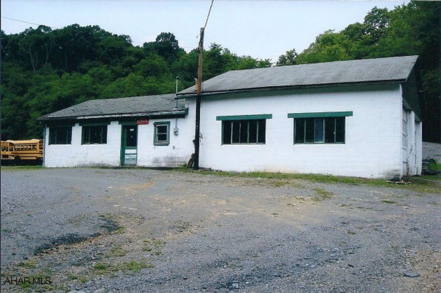 Approximately 1,840 sq. ft. masonry building with two-10' high overhead doors(12' wide)and one-regular size overhead garage door. Ceiling height of approximately 12' in main garage area is reportedly high enough for an above-ground lift (not included). Heat by wood/coal furnace. One-half bath. Office area. 100 A electrical service panel with circuit breakers. Also great for building contractor shop, storage, lanscaping business, plumbing or electrical business. Plenty of onsite parking.