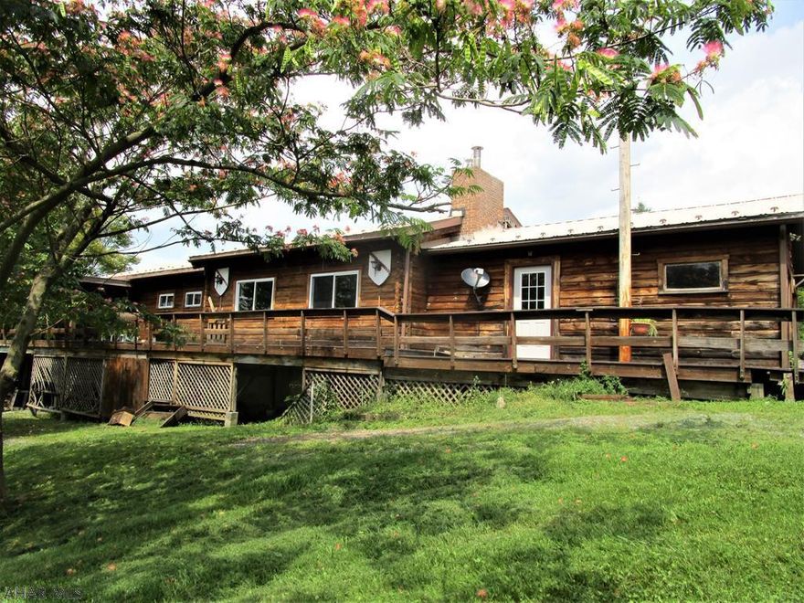 This log home rests in beautiful Milligans Cove and sits on 8.07 acres.  Offering three bedrooms, two baths, living room with a vaulted ceiling, dining room and a kitchen.  Full basement with a workshop area and a ground level walk-out.  Two-car attached garage, oil hot water heat, wood burning stove and a wood fireplace.  Open and wooded land with a pond.  This could be a nice home with some updating!!