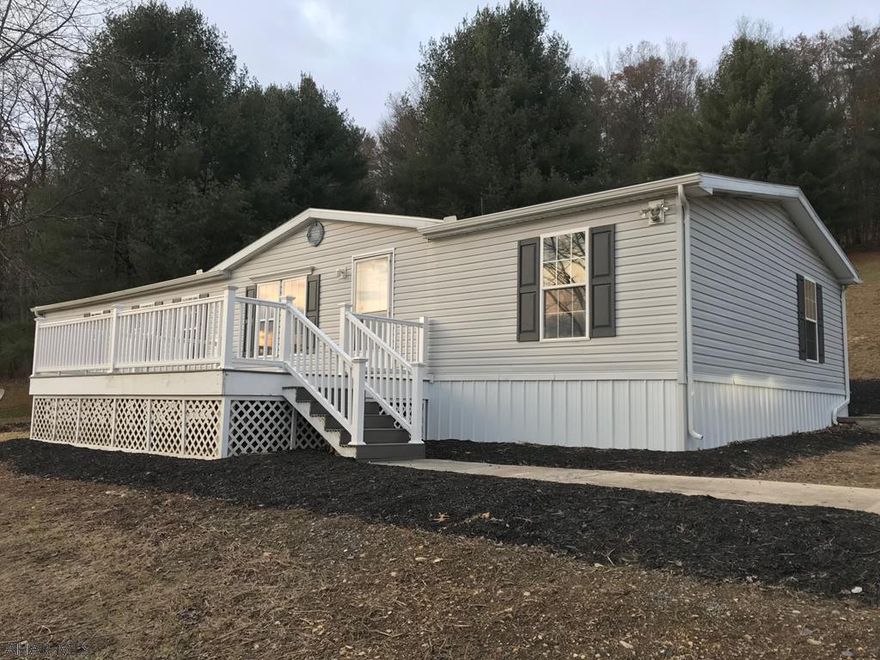 2000 Champion double-wide mobile home resting on 1.683 acres.  Home has four bedrooms, two full baths, living room, kitchen, dining room, family room, and a laundry room. New roof, shutters, metal skirting, floor coverings throughout, appliances, paint, and gravel driveway.  Private well and private septic system. Maintenance free front porch, side porch and rear deck. Nice location and great views.