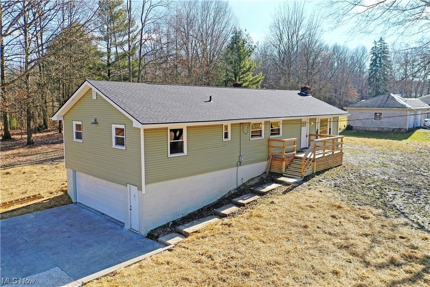 Revel in the tastefully updated living space of this must-see four-bedroom Leavittsburg home! Set off the road in a peaceful, tree-lined setting, this move-in-ready residence awaits with its engaging green exterior and fresh concrete pad that leads into a two-car attached garage with a unique extended bay. A rising sidewalk leads up to the wood trimmed front patio and main entrance where a decorative entry door leads you inside. Here, a sun washed living room wows with its impressive use of natural light thanks to a large picture window. Recessed can lighting aids as it shines down across the ash colored, hardwood styled flooring. The soothing gray and white theme paints an appealing aesthetic as it continues down the main hair and into the nearby combined dining room. Here, sliding doors beckon the expansive rear deck that overlooks the backyard. Slick, stone countertops join a white tiled backsplash and stainless appliances that grace the modern kitchen. Down the hall, an oversized full bath enjoys a splash of color along with an articulately tiled shower and backlit vanity. Four carpeted bedrooms increase in size to finish with a rearward master suite, complete with its own bespoke private bath with more yet elaborate tile work, shiplap trim and a rainwater shower. At the basement level, a fireplace laden family room accompanies both adjacent half bath and laundry services along with an additional bonus room.