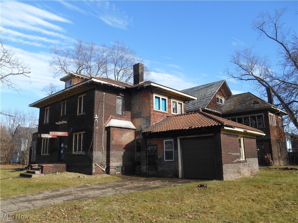 View of home's exterior featuring a chimney, a yard, a garage, and brick siding
