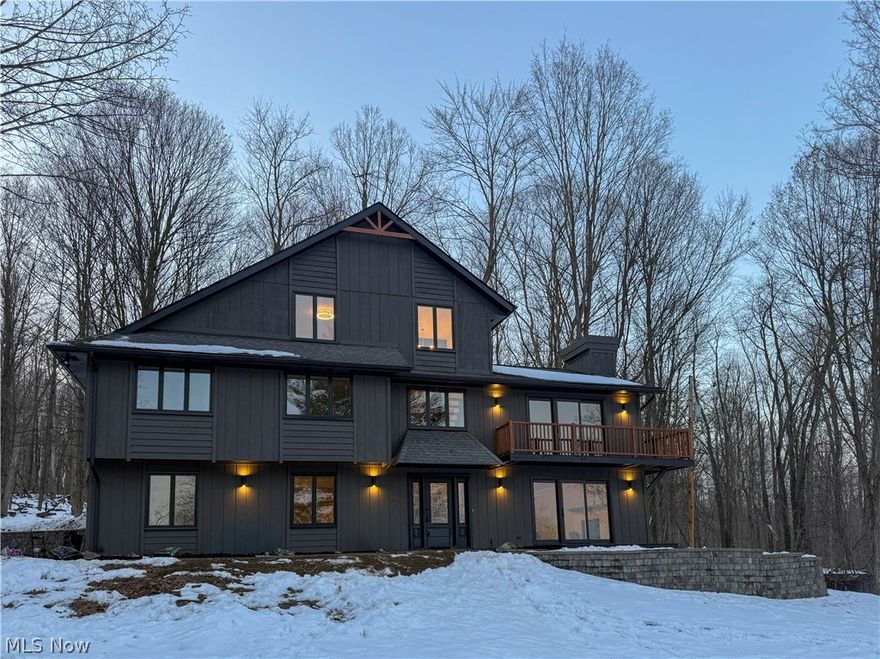 Set on 5.25 scenic acres with a pond and wooded backdrop, this newly updated contemporary home delivers mid-century modern inspiration with a fresh, modern twist. Clean lines, vaulted ceilings, exposed beams, and expansive windows create a bright, airy atmosphere that feels both stylish and serene.

The main level showcases dramatic ceilings, a statement fireplace, and sliding doors that connect seamlessly to a private enclosed balcony, along with an additional set of sliders leading to the expansive rear deck—perfect for enjoying the peaceful, private setting. The fully renovated kitchen features sleek cabinetry, tile backsplash, stainless steel appliances, a coffee bar with floating shelves, and an inviting dining area with direct walk-out access to the large deck, ideal for gatherings.

Three spacious bedrooms with generous closets share a beautifully updated full bath complete with dual sinks, dual mirrors, and a tub/shower combination.

The spacious primary suite occupies its own private level, offering a walk-in closet, bonus storage, and a spa-like bath with dual vanities and a stunning tiled walk-in shower with rain head.

The lower level provides a cozy retreat with a wood-paneled ceiling, fireplace, half bath, and walk-out access to both front and rear patios—perfect for entertaining or simply relaxing in nature.

With updated mechanicals, fresh finishes throughout, and a setting that feels like your own secluded escape, this home is a true private oasis blending modern design with timeless mid-century character.