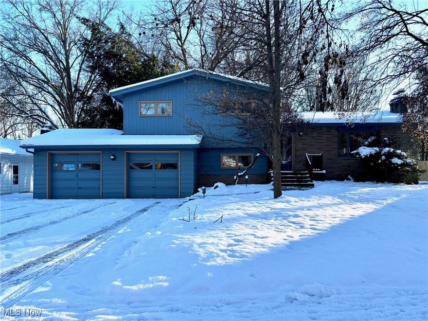 Nestled close to Kent State and the vibrant downtown Kent, this expansive 5 bed, 2 bath multi-level home is set on a half-acre lot along a tree-lined street!  Upon entering through the front door, you'll be welcomed by an abundance of natural light, creating a warm and inviting atmosphere. The formal living room showcases original hardwood floors, a vaulted ceiling with stunning wooden beams, and a cozy wood-burning fireplace, bringing character and appeal to the room.  The dining room flows seamlessly from the living room and sits adjacent to the kitchen, creating a sense of connection.  The spacious kitchen has a fantastic view of the backyard and has a door leading to the rear patio, perfect for outdoor cooking and entertaining.  At the rear of the house, you'll find a large bonus bedroom suite with an exterior door and slider, sitting area, vaulted ceiling with wooden beams, and a closet.   This versatile space can serve a variety of purposes—whether as a bedroom, office, playroom, or anything else you envision. It's truly a bonus area with endless possibilities!  Upstairs, you'll discover three generously sized bedrooms (with original hardwood) and a full bathroom. The lower level features a bedroom, full bathroom, laundry area, and a recreation/family room, offering even more living space. Outside, the home has a hardy Redwood exterior, an attached two-car garage, a large private backyard, and a concrete patio.  This home is perfect, whether you choose to make it your own with updates or embrace its timeless charm as it is.