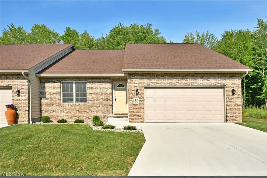 Seize this limited opportunity to own in one of Cortland, Ohio’s most desirable new developments! These custom-built condos are a rare find, offering upscale living in a beautiful natural setting — just minutes from local amenities. This stunning end unit stands out with its classic brick exterior, extra-wide concrete drive, and attached two-car garage. Out back, unwind on the raised deck overlooking a private patio and wooded backdrop, perfect for birdwatching, wildlife, or quiet evenings in the sunroom. Inside, a welcoming entry leads to an open-concept layout with hardwood-style LVT flooring and rustic lighting. Cathedral ceilings with skylights brighten the space, highlighting the central island and chef’s kitchen featuring stone countertops, Bosch appliances, under-cabinet lighting, and a Kraus granite sink. The adjacent dining area flows seamlessly into the living room, complete with recessed lighting and a stone fireplace with oak mantle. Two spacious bedrooms are thoughtfully separated by storage closets. The guest suite is filled with natural light and sits near a full bath with matching finishes, while first-floor laundry adds convenience. The impressive master suite offers generous space, a walk-in closet, dual vanity, and a beautifully tiled walk-in shower. A full basement with high ceilings provides abundant storage and potential.