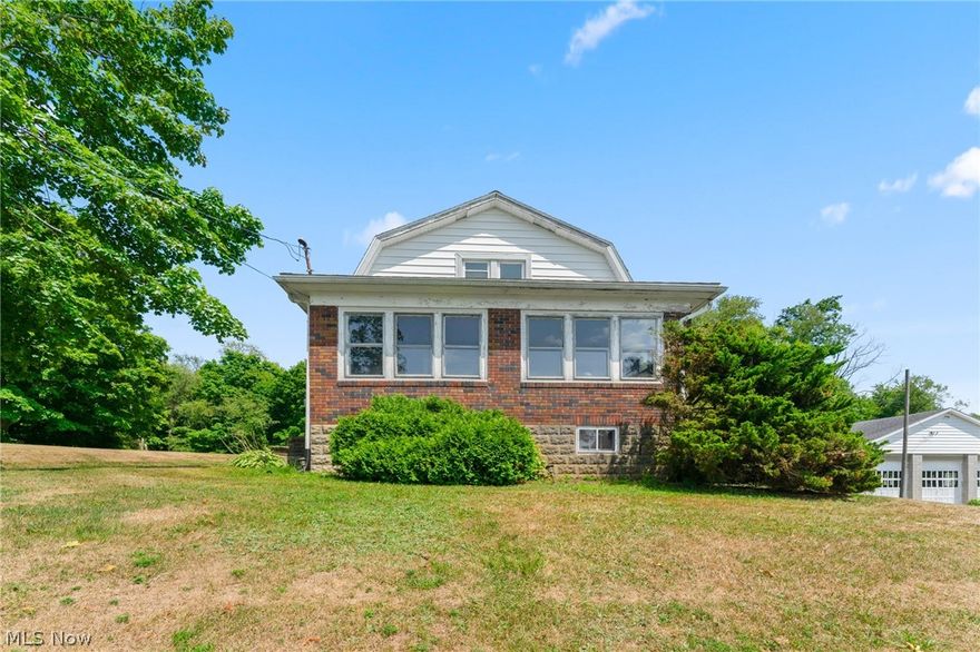 Take a look at this 3 bedroom home on 2 acres in West Branch Local School District. As you enter the circular driveway and step into the front door you notice the character of the original woodwork. The front sunroom leads to the living room with arched opening to a den. The galley kitchen has original wood cupboards and an eating area. There are first floor laundry hook ups off of the eating area. Around the corner there is a first floor bedroom and the full bath. The second floor contains two bedrooms and a loft area at the top of the stairs. Full basement with walk out. There is a large block outbuilding with three overhead doors and a separate drive. Updates include septic 2020, roof on home and garage, A/C unit, and vinyl windows on the second floor.