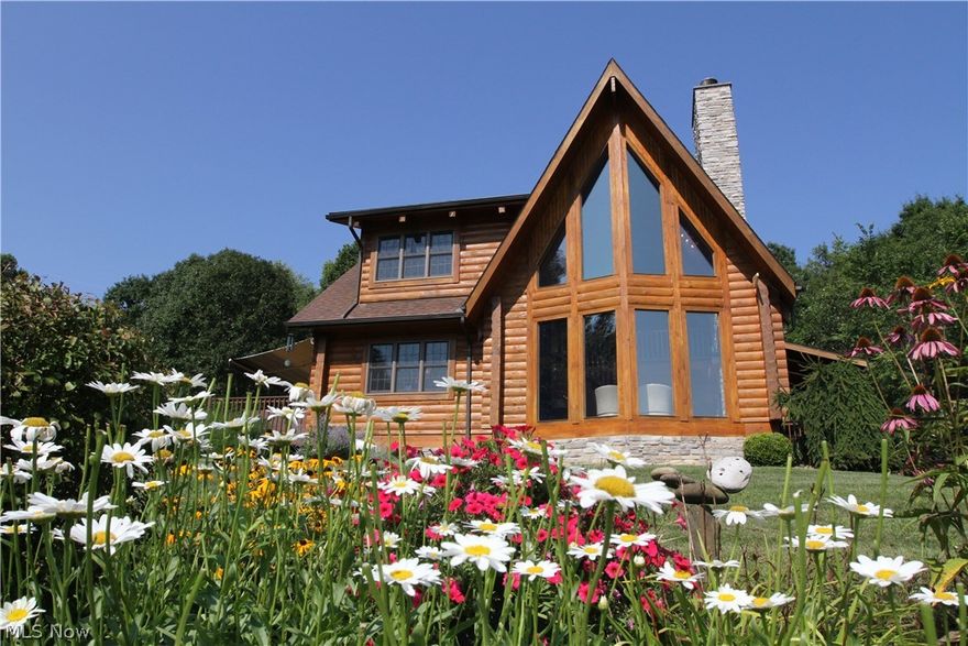 Custom built log home with gorgeous country setting and breathtaking hilltop view.  Amish built with poured wall foundation, solid wood floors and doors, open floor concept with cathedral ceilings, floor to ceiling windows, beautiful stone fireplace, custom built kitchen with breakfast bar, solid wood cabinets, granite counter tops and stainless steel appliances, dining room overlooks back deck w/Sunsetter awning, pond & private backyard.  Upstairs loft includes owners’ suite with private bath w/Jacuzzi tub, walk in closet and bonus room.  Two car attached garage, full basement which could easily be finished, home is meticulously maintained inside and out.  Additional detached log building with three rooms, garage, workshop and studio that could easily be converted for additional living space or in-law suite.  Studio opens onto stamped patio with fire pit overlooking the pond creating a serene, quiet setting.  Beautiful fruit, vegetable, herb and flower gardens are an added bonus.  Sit