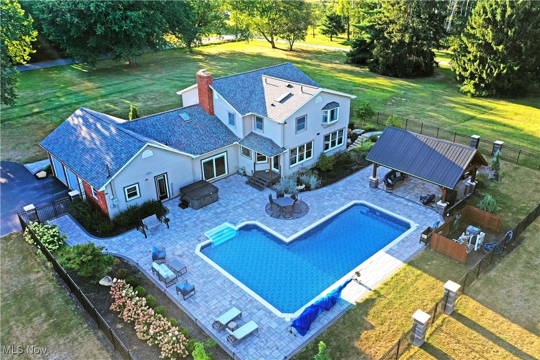 Pack your bags, your personal backyard paradise awaits at this remarkable Canfield estate! Nestled on nearly eight acres of private seclusion in a highly desirable location, this property delivers the perfect blend of serenity and convenience, just moments from top-rated restaurants, shopping, and entertainment. Boasting two full floors of finished living space plus a walk-out basement complete with a game room, there’s truly something for everyone. A long blacktop driveway transitions to cement as it approaches a spacious outbuilding, ideal for equipment or vehicle storage. Out back, escape to an expertly designed, fully fenced oasis featuring a stone terrace with coordinating walkways. Enjoy peaceful evenings beneath the large pavilion, listen to the burbling fountain, or gather around the natural gas firepit, every detail thoughtfully crafted with breathtaking views in mind. Step inside to find a grand foyer flanked by a private home office and a gracious living room, both accented with hardwood-style flooring. The main hall leads past the open staircase to an impressive kitchen, where a massive island, professional-grade gas range, stainless steel appliances, and stone countertops create a true chef’s dream. Casual dining enjoys scenic poolside views, while the adjacent window-lined sunroom transitions beautifully into a formal dining space. Step down into the cozy family room, where a towering brick fireplace takes center stage. Nearby, you'll find a convenient full bath and first-floor laundry, adding everyday practicality to the home’s thoughtful layout. Upstairs, four generously sized bedrooms line the hall along with a beautifully updated full bath. The oversized master suite is a true retreat, showcasing a large walk-in closet and dressing area, plus a show-stopping spa bath featuring a glass-lined water jet shower, soaking tub beneath a starlight ceiling fixture, and a cozy fireplace that sets the mood.