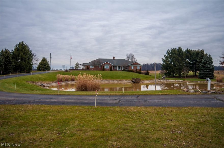 Over 3 aces of rural oasis, a park like setting, close to town. Towering pines accent a well stocked, well maintained pond. The brick ranch home is quality throughout, custom built and ready to move in. Seasonal gardens, both floral and vegetable are situated along with varieties of fruit trees and perennial berries. An irrigation system allows for constant production of vegetables from raised beds. A spacious floor plan, Schrock cabinetry, storage in every possible space, and panoramic views from every room, make this home one you can enjoy if "out of the town busy-ness" is to your liking. Enjoy the breakfast on the end enclosed patio and see deer roam the fields. The dining area is open for entertaining large groups or family, especially at holidays. Two large main floor bedrooms each have a full bath. In addition, there is a large family room and formal living room with fireplace. A finished basement with an additional bedroom and full bath has a walkout to another patio. All plumbi