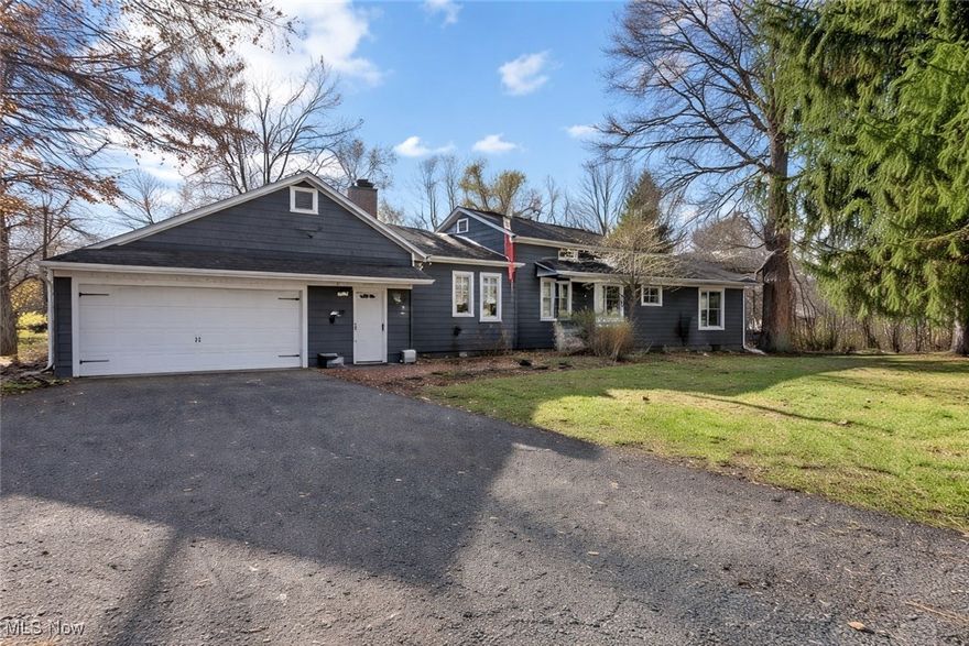 Discover a rare blend of timeless craftsmanship and modern comfort in this distinctive Mentor home. Enjoy historic craftsmanship without the limitations of historic designation, including original solid-board construction, hand-hewn framing, and traditional dowel-peg joinery—details rarely found in today’s homes. Hardwood flooring is present beneath the carpeting in select rooms. The eat-in kitchen features quartz countertops, a large quartz island, ample cabinetry, and updated lighting, creating an inviting gathering space. Two wood-burning fireplaces anchor both the dining area and the living room, which also features wood-beam ceilings and a wet bar for entertaining. The first-floor primary suite provides a private retreat with custom built-ins and a jetted tub, creating a comfortable space to unwind. The home is set on a beautiful wooded lot with a gently flowing stream, providing a peaceful, natural backdrop for outdoor enjoyment. Raised garden beds enhance the outdoor space, while a four-car garage provides ample room for vehicles and outdoor equipment.