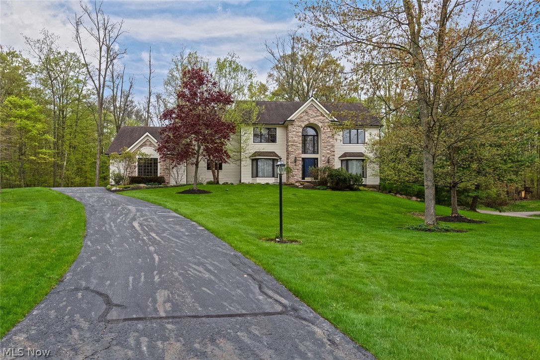 Welcome home to this magnificent Chagrin Falls colonial situated on a serene 2 acre lot! As you step inside, you will immediately appreciate the two-story foyer and gleaming hardwood floors that flow throughout the main level. The living room opens to the formal dining room, which features a tray ceiling. You are sure to fall in love with the spacious eat-in kitchen, which boasts granite countertops, stainless steel appliances, a large pantry, and a sunny eat-in area with deck access. The stunning two-story family room is located just off of the kitchen and features a stone fireplace, built-ins, skylights, a wall of windows deck access. An office with built-ins, a convenient laundry room, a full bath, a half bath, and a bonus room complete the first floor. Upstairs, you will find the spacious master suite, which features a walk-in closet and a luxurious en suite bath with double vanities, a soaking tub, and a step-in shower. Three spacious bedrooms and another full bath with double sin