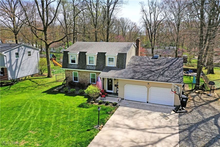 Find all the space you’ve been wanting and more with this expansive Canfield residence! Beautifully updated and full of style, this home presents a bevy of impressively sized rooms from top to bottom plus a fantastic, fenced-in backyard. Located in a desirable neighborhood, just minutes from downtown Canfield, this substantial estate boasts plenty of curb appeal with its brick accent work and manicured landscaping that offsets the sweeping cement driveway. Tall trees provide a park like setting as the backyard, showcases its elevated deck work, lower patio and multiple garden spaces. A large shed accompanies a must-see firepit for evening gathering, topping things off. Inside, a gracious foyer runs along a wooden staircase as the expansive living room opens to reveal its hardwood styled flooring and soft lighting. Around the far corner, formal dining enjoys a rustic bar area and plenty of sunshine. The elaborate central kitchen features wraparound countertops that include additional bar top seating as the tiled flooring runs underfoot. Sliding doors light the eat-in dining space as a sizeable family room drops down from the opposite corner. Here, exposed trusswork pairs with a towering brick mantle with fireplace. A colorful half bath completes the floor. Upstairs, an additional oversized bath is steps from the landing as three generous bedrooms line the hall. The master bedroom includes its own full private bath. Downstairs, laundry and central storage join a home gym area.