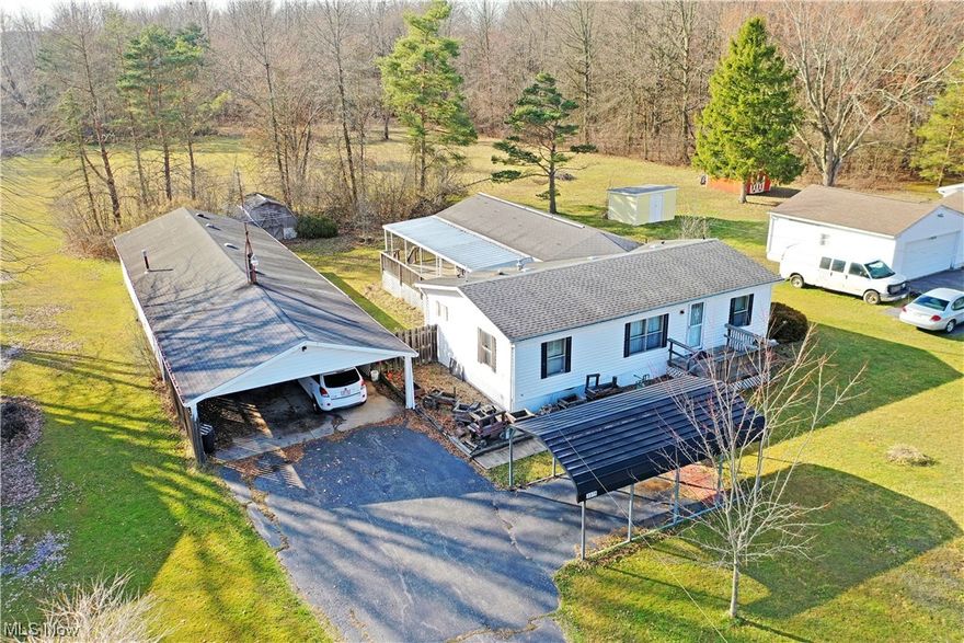 Surprise yourself with the impressive amount of living space and accompanying storage all offered by this move-in-ready Cortland ranch! Just one look at this home and you’ll immediately notice just how far back both the must-see addition and the nearby garage sweep back towards the tree line. Additional covered notables include a frontal single carport, attached dual car port and a fantastic, covered deck space running alongside the home, perfect for cooking and entertainment alike. A raised front porch leads you inside the home as you immerse yourself in the warm wood paneling and lush carpets below. The spacious great room provides ample dining space as it transitions into the nearby kitchen. Here, a serving window joins a host of like styled cabinetry within its galley layout. Laundry services are found just steps away as they conjoin the pass-through full rear bath; also accesses privately by the near bedroom. Opposite the living room, the master bedroom suite includes its own oversized full bath and additional closet storage. The hall-like rear addition steals the show with its expansive footprint that includes side patio access and a corner fireplace.