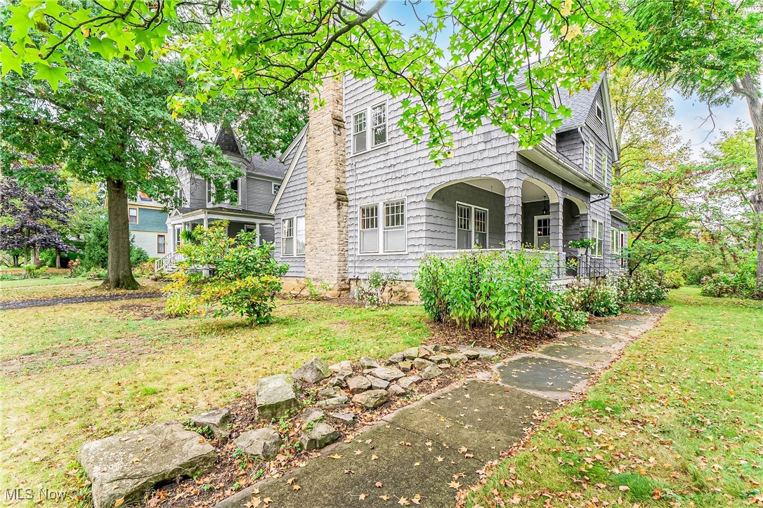 Unlike anything else in Oberlin. This New England-style century home with shingled façade, massive stone chimney, a welcoming porch with graceful arched openings, set a timeless tone, while a broad gabled roof punctuated by dormers hints at the expanses within. Step from the stone steps onto the breezy porch, then into a warm inviting foyer where the sculpted staircase rises in gentle curve and a windowed landing pours in soft light—an everyday reading perch in the heart of the home. Beyond French doors, the living room runs the full width of the house, wrapped in windows for sun-splashed mornings and golden afternoons. Throughout the first floor, original oak floors, exquisite millwork, built-in china cabinets in the dining room, and a stone-carved fireplace mantel create that rare blend of craftsmanship and comfort. The large eat-in kitchen overlooks the backyard and features a handy side entrance plus a pantry. A welcoming den and flexible first-floor guest room/library, along with a half bath and back staircase, make daily living effortless. Upstairs, oak floors pair with painted woodwork for a calm, airy feel. You’ll find five bedrooms and two full baths, including an expansive, elegant primary suite with two generous walk-in closets. Just off the luminous landing, a charming nursery-style bedroom offers an ideal sleep space, studio, or reading room. Practical touches keep everything easy: lower-level laundry with sink, washer & dryer; abundant storage in the basement, walk-up attic, and plentiful closets—including a walk-in hall linen closet on the second floor. Thoughtful updates include a 2024 roof, newer electrical panels, boiler, and a high-efficiency water heater. Out back, the property unfolds into an absolutely beautiful, private yard with a large stone patio for alfresco dinners, established plantings and mature trees, and—at the very rear—a small woodland-like garden that feels worlds away. A two-car garage completes this rare Oberlin estate.