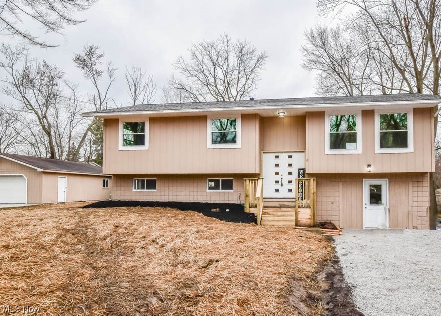 Discover this stunningly renovated bi-level nestled on three parcels totaling half an acre! This home has undergone an extensive transformation, boasting a brand-new roof, windows, decks, doors, lighting, flooring, as well as a completely revamped kitchen and baths. The main level reveals an inviting open layout between the living and dining areas, seamlessly connecting to the new back deck for indoor-outdoor living. Be the 1st to prepare meals in the updated kitchen complete with stainless steel appliances, butcher block countertops, and a tasteful tiled backsplash. Down the hall you'll find three bedrooms and two full baths, including a master suite with its own private full bath. The versatile lower level adds a spacious rec room, a bonus room adaptable as a spare bedroom or home office, with a convenient half bath, and a cozy family room with a separate entrance. The peaceful, private setting is perfect for nature lovers tucked at the end of a no thru traffic street with mature trees, wildlife and a 2 car detached garage for parking and storage.  Located in Barberton's desirable West side, this like-new home is just minutes away from McCafferty Park where you can enjoy picnic tables, playground equipment, baseball fields, basketball courts and more! Don't miss out, call to see this amazing home today!