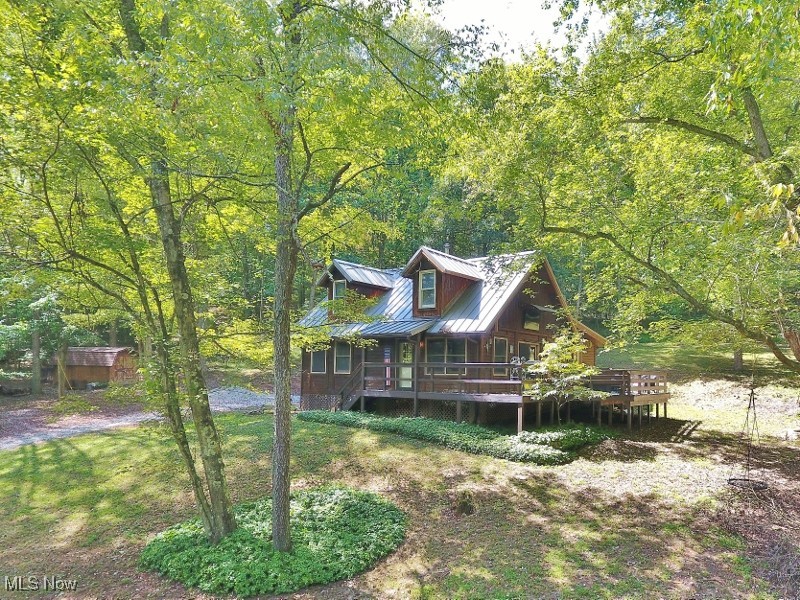 The best of both worlds awaits with this 3-bedroom log-sided home, ideally situated on 8.56 wooded acres yet only ½ mile from 1540 acre Atwood Lake and can easily be walked. A private dock slip is included, giving you easy access to explore all 1,540 scenic acres of the lake. Nestled in the desirable Whispering Pines community, this property also adjoins 120 acres of Muskingum Watershed public hunting land, offering endless outdoor recreation. This turnkey home is being offered fully furnished and beautifully decorated—just bring your clothes and groceries to start enjoying your retreat. The main floor boasts an open-concept layout with natural wood flooring, a great room with soaring vaulted, beamed ceilings, and a cozy wood-burning stove. Two bedrooms, a full bath with laundry, and a spacious loft overlooking the great room (perfect as a third bedroom and office) provide plenty of living space for your family and friends. Step outside to a wraparound deck overlooking a large yard, complete with an outdoor TV for entertainment. Outdoor enthusiasts will appreciate the three tree stands and feeders that remain with the property. Additional highlights include a storage shed with two mowers, a new mini-split heating and cooling system, a metal roof (2017). Propane wall heater in addition to the mini split system and wood stove. Spectrum high-speed internet and cable available. With no neighbors in sight yet so close to Atwood Lake, this property offers unmatched privacy, tranquility and entertainment. Immediate occupancy is available at closing. Schedule your personal showing today and don’t miss the 3D virtual tour!