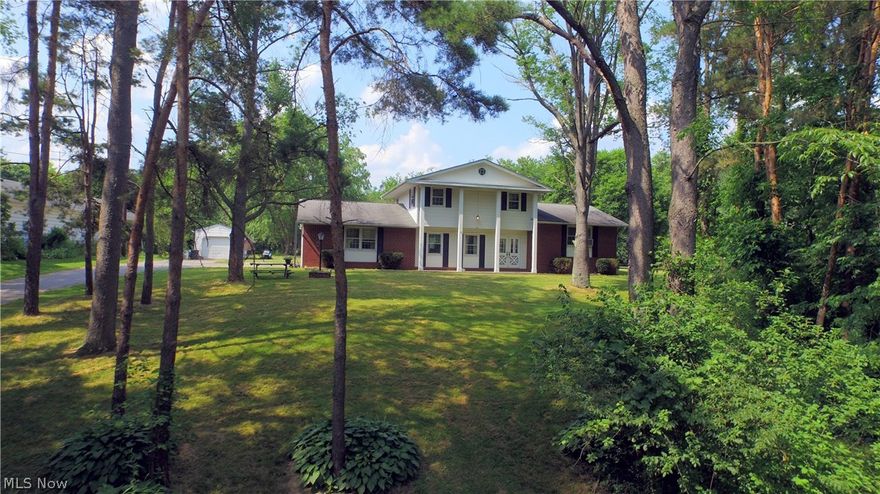 This large 1975 built home sits deep into the property in a rural Warren, Ohio setting. With heavy tree coverage and a long, private driveway, you feel the sense of security and removal from your usual surroundings. Sitting at the top of the property, the home boasts large prominent pillars giving off a strong presence of strength and class. The half brick has many windows and a large set of glass trimmed doors provides the formal entry way. Inside, the split level design maximizes space, placing bedrooms upstairs and leaving plenty of traditional living space on the mid level. The tiled foyer leads to an elevated living room or a mid level carpeted den; both wrapping around to the kitchen. A first floor bath and laundry separate the den side and lead to the garage, while the elevated living room boasts hardwood style flooring and leads to a formal dining area in a well lit room offset from the kitchen. Inside the kitchen you will find dark wooden cabinetry and unique tile countertops.