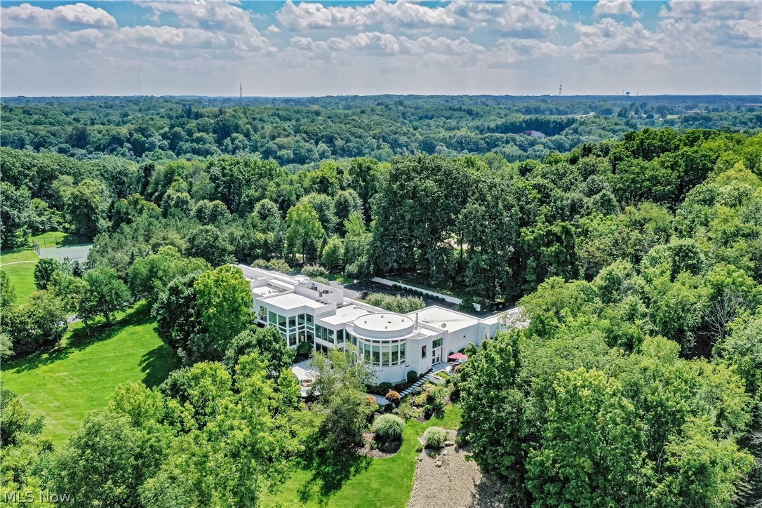 Perched at the edge of the Cuyahoga Valley National Park, this exquisite, contemporary masterpiece was designed to be appreciated from both near and afar, an exuberant expression, that, like a symphony, cannot be contained within its walls. A winding drive ascends to the front entry, lined by lush landscaping that shields the home from view. Double doors open to the foyer, unveiling sight lines to the north, east, and west walls of the home, a prelude to the composition to come. Ahead, the double height living room is wrapped in a dramatic wall of windows with a lofted seating area tucked away above. Distinct entertaining areas flow together seamlessly, with split-stair levels ascending and descending like musical scales. Ascend to the grand dining room above, or descend to the stylish club level below, a sophisticated space complete with a stunning home theater, bar, wine cellar, and full guest suite. A dramatic gallery wall runs the North-South axis of the home, leading from the kitchen and circular great room to the private bedroom wing. Throughout the home, glass doors open to exceptional outdoor living areas - terraces overlook the gently sloping backyard, and a granite patio spans the back of the home. The 7-car garage - heat controlled - provides a sanctuary for those who appreciate automotive engineering as much as art and music. A true architectural gem, this home is unlike anything in the region. Schedule a private viewing to experience it firsthand. All furniture is available and negotiable.