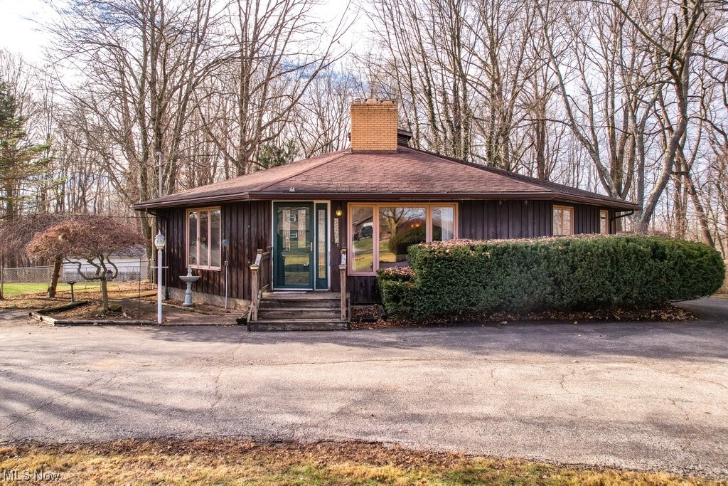 Rare Opportunity! Modern design meets classic charm in this unique Octagonal style Ranch situated on a tranquil and .45 acres wooded lot in Rootstown Township. This spacious 4 Bedroom/1.5 home with its distinctive circular floorplan of 1900 sq ft of living space is full of charm and possibilities for its new owner. Feel like you have escaped to your private retreat as you enter the living room with its sweeping wood-beamed cathedral ceiling, knotty pine walls and brick wood-burning fireplace with potential as a pass-through to share with the cozy and centralized family room - a perfect gathering spot for friends and family. Enjoy the beauty of nature from your private deck, perfect for entertaining or simply unwinding amidst the peaceful surroundings. The Primary Bedroom features a private balcony that overlooks the wooded fully-fenced backyard. A main floor laundry room provides the convenience and ease of single level living. Plentiful storage is available in the partial basement, large attic, spacious 2-car attached garage and shed. An oversized circular driveway makes parking a breeze. NEW furnace installed on 1/8/2024. Newer hot water tank (2022) and Septic Aeration System (2012). A 1-year Home Warranty is included for peace of mind. With its fantastic location just minutes from I-76, NEOMED, and West Branch State Park, don't miss the opportunity to make this exceptional house your new home. Make your appointment to come see this home today!