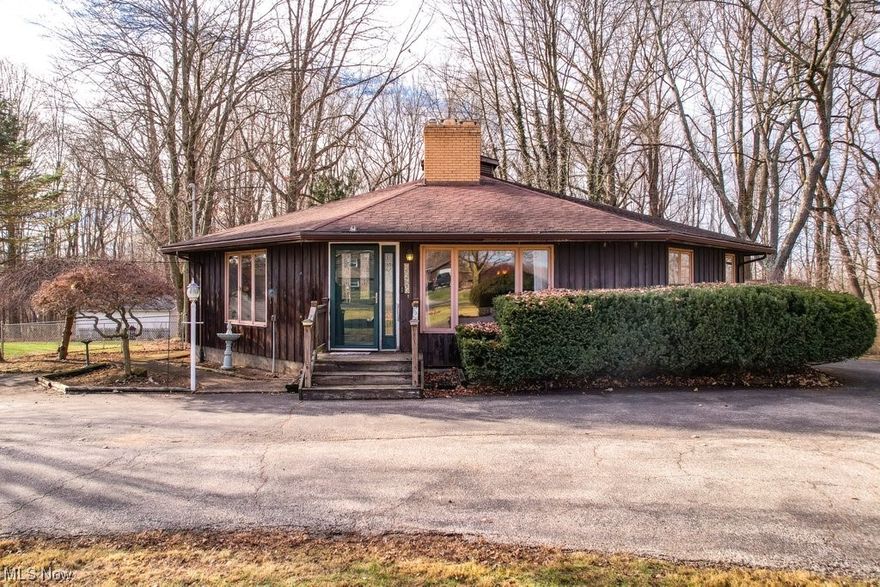 Rare Opportunity! Modern design meets classic charm in this unique Octagonal style Ranch situated on a tranquil and .45 acres wooded lot in Rootstown Township. This spacious 4 Bedroom/1.5 home with its distinctive circular floorplan of 1900 sq ft of living space is full of charm and possibilities for its new owner.  Feel like you have escaped to your private retreat as you enter the living room with its sweeping wood-beamed cathedral ceiling, knotty pine walls and brick wood-burning fireplace with potential as a pass-through to share with the cozy and centralized family room - a perfect gathering spot for friends and family. Enjoy the beauty of nature from your private deck, perfect for entertaining or simply unwinding amidst the peaceful surroundings. The Primary Bedroom features a private balcony that overlooks the wooded fully-fenced backyard. A main floor laundry room provides the convenience and ease of single level living. Plentiful storage is available in the partial basement, large attic, spacious 2-car attached garage and shed. An oversized circular driveway makes parking a breeze. NEW furnace installed on 1/8/2024. Newer hot water tank (2022) and Septic Aeration System (2012). A 1-year Home Warranty is included for peace of mind. With its fantastic location just minutes from I-76, NEOMED, and West Branch State Park, don't miss the opportunity to make this exceptional house your new home. Make your appointment to come see this home today!