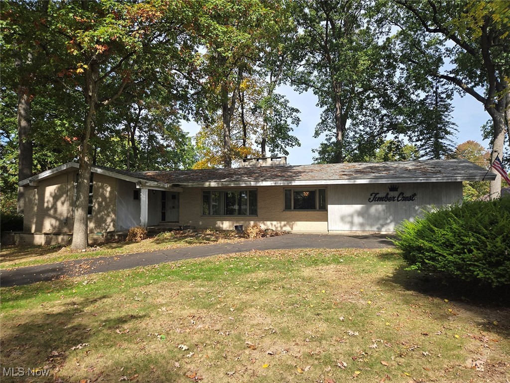 This 1960 brick and wood ranch home offers 2,036 square feet of solid mid-century character on a beautiful three-quarter acre corner lot surrounded by mature, stately trees. The home features a well-designed floor plan with spacious living areas, including a kitchen that flows into the living room and dining area with a fireplace, as well as a formal dining room that opens to a sunken family room with its own fireplace. Spacious bedrooms throughout, including the primary bedroom with a full bath and two closets. Two additional bedrooms share a Jack and Jill bath, and there is a full guest bathroom for convenience. A mudroom provides a practical entryway, while the partial walkout basement includes laundry, breaker electric, and a gas F/A furnace. The attached two-car garage, rear deck, and two enclosed porches are perfect for enjoying the tranquil, tree-lined setting. Well and public sewer. Parcel #2300321. Located just minutes from Hartville, this home sits in a desirable area with genuine character. It's ready for someone to bring their renovation ideas and personal style to restore this mid-century gem to its full potential.