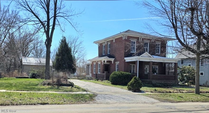 Stately, well kept, mini mansion located in the heart of Ravenna! This historical home has so much charm with lots of original woodwork including doors, floors and millwork, elegant radiators, grand staircase and brick exterior with architectural corbels. This is a true five bedroom home with the potential to have a sixth bedroom or office if you need that option. Two laundry areas with one on the first-floor and the other is in the full walk-out basement that has so much additional space!  Enjoy your summer days from the front or side covered porches overlooking the additional lot that comes with its own address. Large storage barn with a walk-up attic that can be turned into an art studio or hobby room! Landscaping, mature trees including a gorgeous magnolia and areas for gardening! New roof on the house in 2024 and new metal roof on barn in 2025. Other updates include new stove and refrigerator, interior paint, updated bathrooms, newer boiler and lots more! Located within walking distance to downtown.