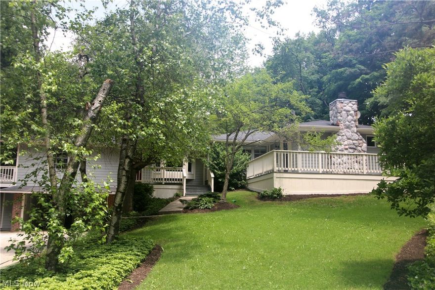 Sprawling updated raised ranch style home set on a bucolic wooded acre. This charming 4-bedroom home features a light-filled living room with a magnificent river stone fireplace and bay window. A good sized family room opens to an updated eat-in kitchen with newer cabinets, granite counters, bay window and large first floor laundry room/pantry. The very private master suite features a 2nd fireplace, large walk-in closet, updated master bath, and sliders leading to a wrap-around deck.  The home includes three additional bedrooms, another updated bath plus a den/study with built-in bookshelves. The main rooms including the living room, family room, kitchen and master have hardwood floors. Newer furnace '17"and AC '14. Septic installed 2017. New roof installed 2018.  Workshop and 2 car garage on lower level. Award winning Chagrin Falls schools. Geauga taxes.