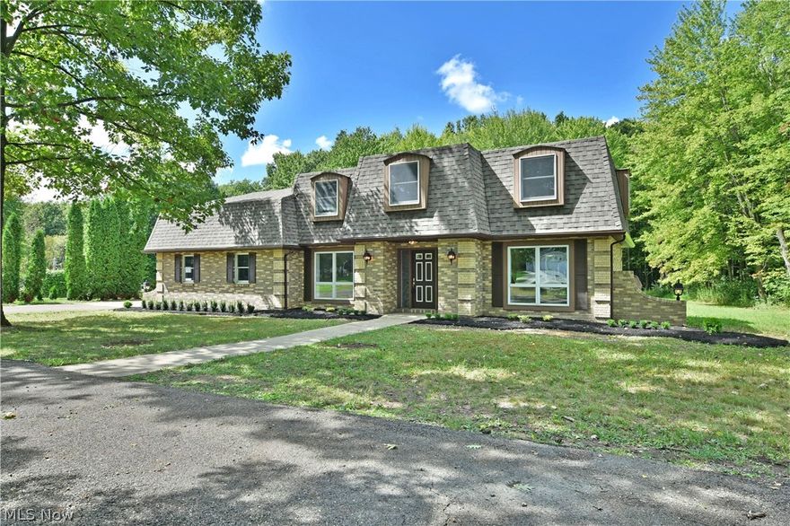An estate to be seen, this all brick two story McDonald home offers a three plus potential bedroom layout filled with masterfully remodeled living space! Set deeply into a tree lined lot, a sweeping horseshoe driveway wraps around the front of the residence before branching off into a cement landing where a combined four car garage is located. Powerful dormer windows overlook the front yard as tidy landscaping leads into the decorative entry door. A substantial foyer greets you with a sweeping, carpeted staircase leading to the second floor living suites. An illustrious living family room steps down nearby while opposite, a like styled dining room enjoys bespoke lighting and tall windows that illuminate the adjacent kitchen. Here, multiple granite counters run along the wall and island, leading towards first floor laundry and a half bath. A rearward living room completes the floor with a brick mantle and French awaiting the rear patio. Upstairs, a trio of spacious, carpeted bedrooms li